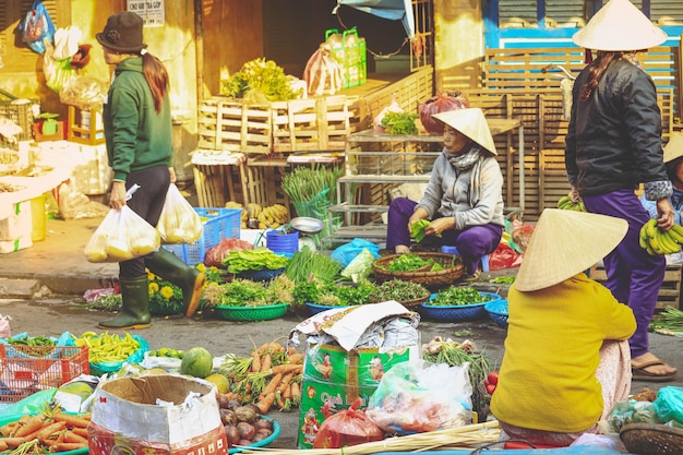 Foto hoi an vietnã 7 de fevereiro de 2018 foco suave em mulher vietnamita vendendo legumes em um mercado à beira da estrada na província de hoi an quang nam vietnã