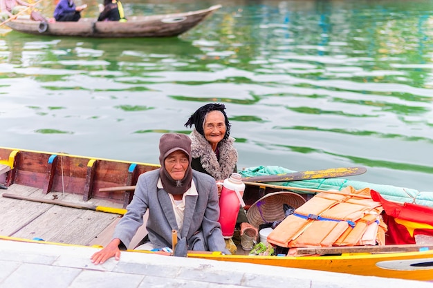 Hoi An, Vietnam - 16 de febrero de 2016: Familia vietnamita mayor en un barco en el terraplén del río Thu Bon en Hoi An, Vietnam