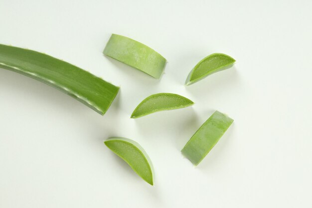 Hoja de aloe vera y rodajas sobre fondo blanco.