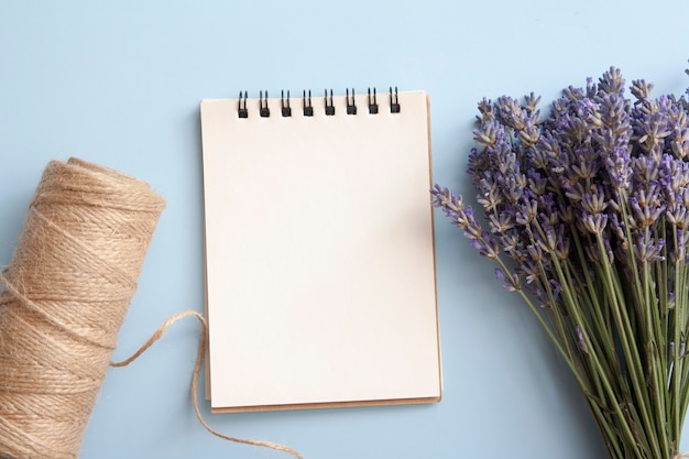 Hoja en blanco de cuaderno plano con lavanda, hilo.