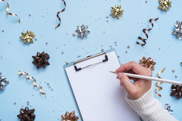 Hoja en blanco de la tableta y lápiz en mano femenina sobre fondo de color Escriba su texto de Navidad o Año Nuevo