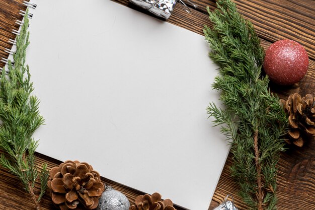 Hoja de cuaderno en blanco para espacio de copia con abeto, ramas de abeto y juguetes de árbol de Navidad