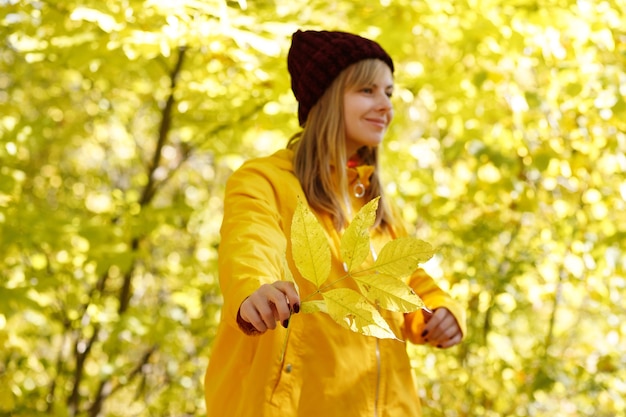 Foto hoja de otoño amarillo en la mano de una mujer delante del fondo amarillo brillante de otoño