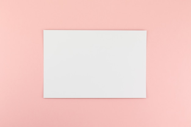 Foto hoja de papel a4 en blanco sobre fondo rosa
