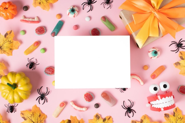 Una hoja de papel blanca sobre un fondo de Halloween con calabazas y arañas sobre un fondo rosa claro con un lugar para texto Espacio para copiar Vista superior de posición plana