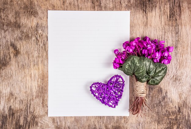 Hoja de papel en blanco, corazón y flores.