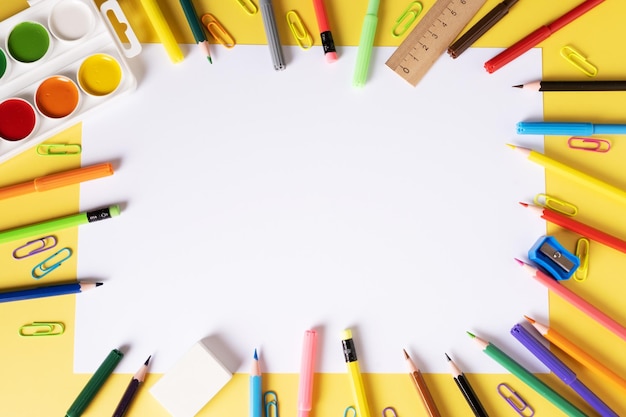 Una hoja de papel en blanco con lápices de colores, marcadores, pinturas de acuarela, desecha una regla