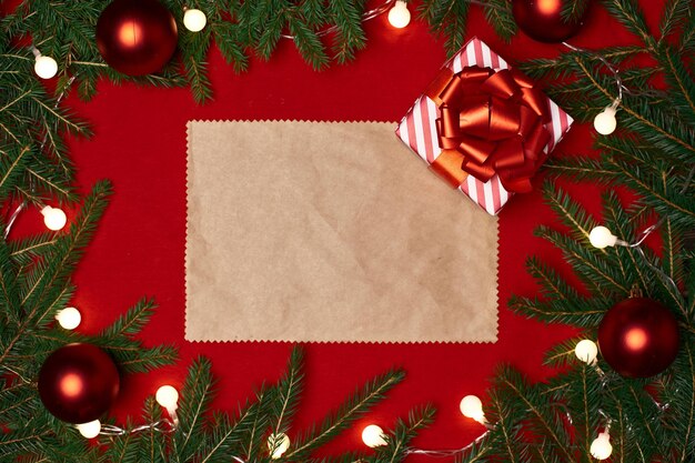 Foto hoja de papel en blanco y un regalo de navidad y sobre un fondo rojo festivo.