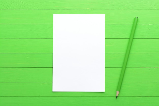 Una hoja de papel en blanco sobre un fondo de madera verde