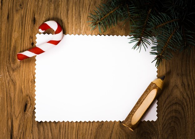 Foto hoja de papel en blanco sobre el piso de madera con un lápiz y adornos navideños