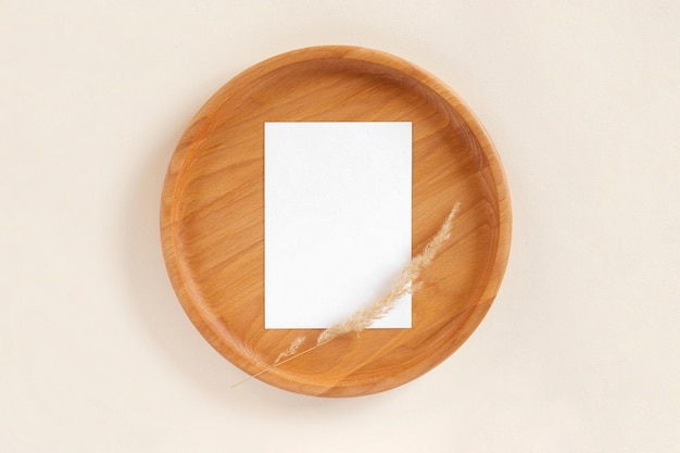 Hoja de papel en blanco sobre placa de madera fondo beige pastel Maqueta de tarjeta Sombra de diseño de boda elegante