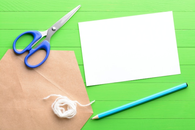 Una hoja de papel en blanco con un sobre sobre fondo de madera verde