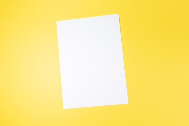 Hoja de papel blanco vacía y maqueta de fondo amarillo