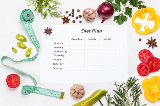 Hoja de papel con plan de dieta para la semana con cinta métrica y verduras