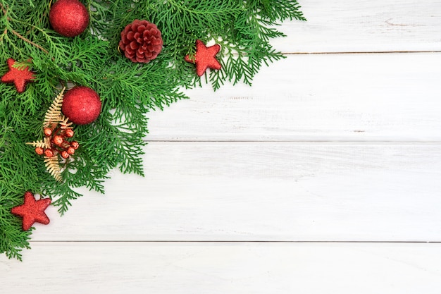 Hoja de pino con estrella roja y decoración de bola de Navidad en el tablero de madera blanca