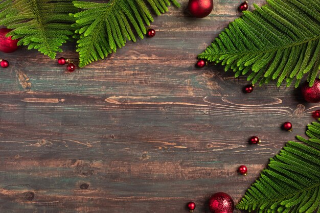 Hoja de pino de Navidad con decoración de adorno rojo sobre mesa de madera