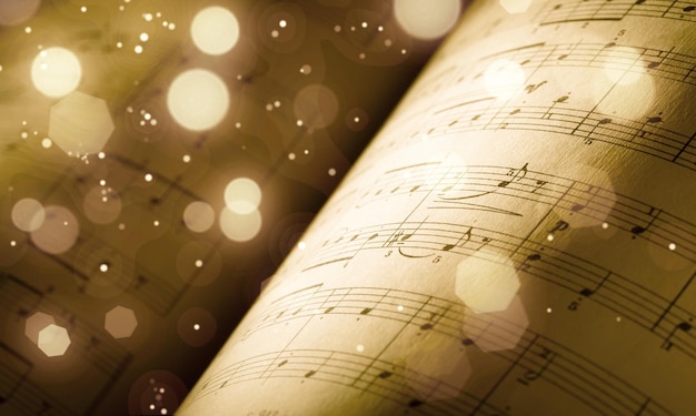 Foto hoja vieja con notas musicales navideñas como bokeh de fondo