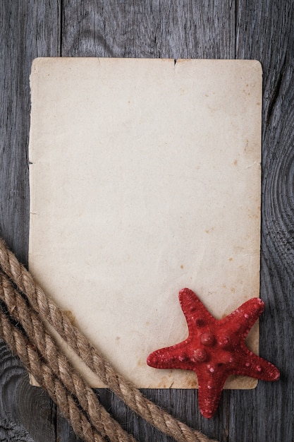 Foto hoja vieja de papel con cuerda y estrellas de mar sobre tabla de madera con espacio de copia