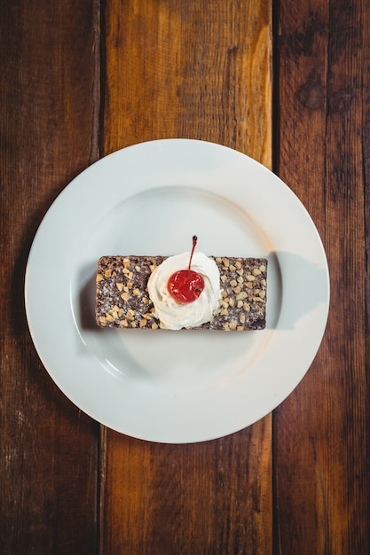 Foto hojaldre con crema batida y cobertura de cereza en plato