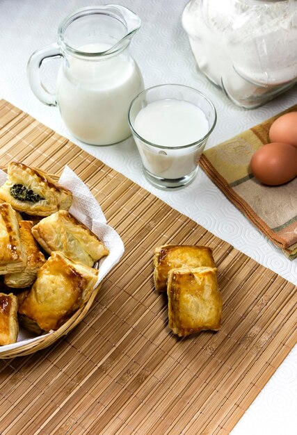 El hojaldre con espinacas y queso feta en una cesta de mimbre y leche en el primer plano de la mesa