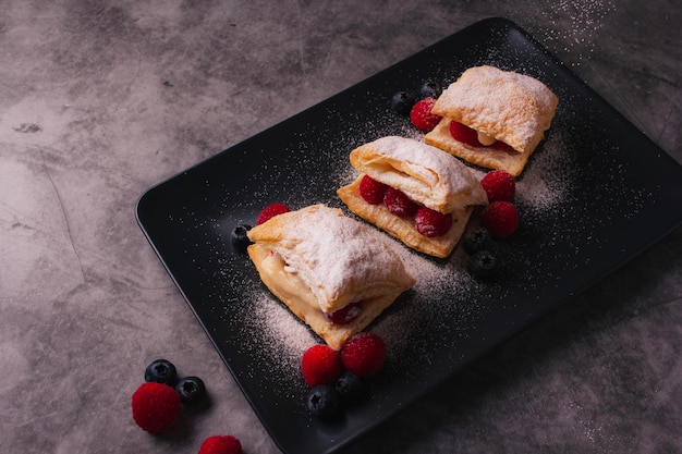 Hojaldre con frutos rojos y azúcar en polvo sobre fondo oscuro