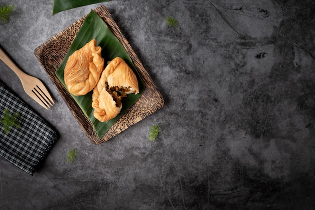 Hojaldre de pollo al curry, merienda tradicional tailandesa sobre fondo negro