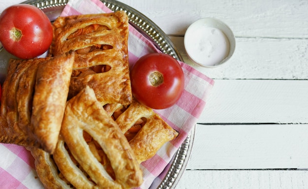 Hojaldre con tomate en una mesa de madera blanca con espacio de copia