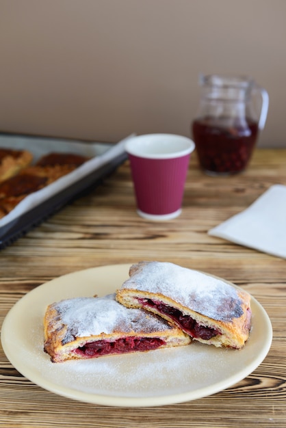 Hojaldres con cereza y una bebida en una mesa de madera.