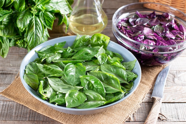 Hojas de albahaca fresca en un recipiente con agua sobre una mesa de madera. Albahaca verde y morada. Concepto de alimentación saludable.