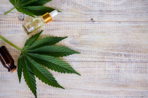 Hojas de cannabis sobre fondo de madera con botellas, aceite de cannabis. Enfoque selectivo