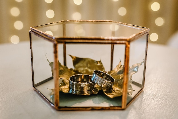 Hojas doradas secas con anillos de boda en una caja de metal Decoración de boda elegante de lujo para la ceremonia Compromiso de estilo otoñal