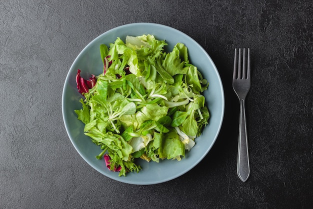 Hojas de ensalada verde en un tazón sobre mesa negra