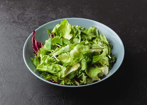 Hojas de ensalada verde en un tazón sobre mesa negra