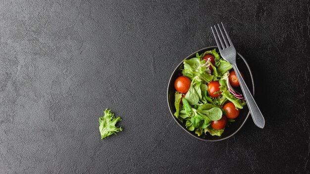 Hojas de ensalada verde en un tazón sobre mesa negra