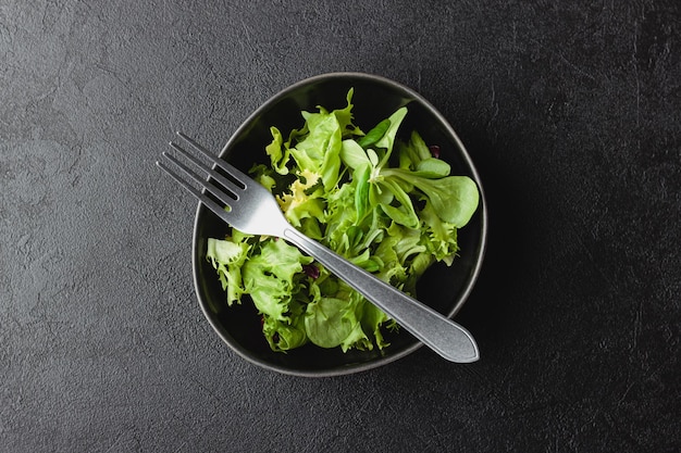 Hojas de ensalada verde en un tazón sobre mesa negra