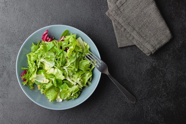 Hojas de ensalada verde en un tazón sobre mesa negra