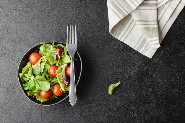 Hojas de ensalada verde en un tazón sobre mesa negra