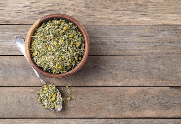Hojas y flores de té secas de manzana en un cuenco sobre una mesa de madera con espacio para copiar