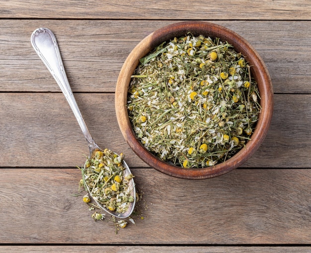 Hojas y flores de té secas de manzana en un cuenco sobre una mesa de madera