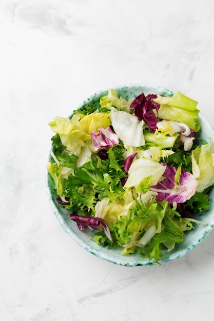 Hojas frescas de ensalada diferente en plato de cerámica