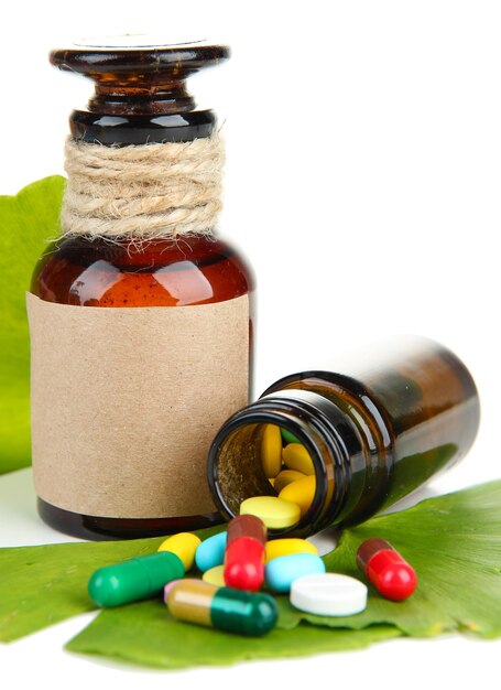 Hojas de ginkgo biloba y frascos de medicamentos con pastillas aisladas en blanco