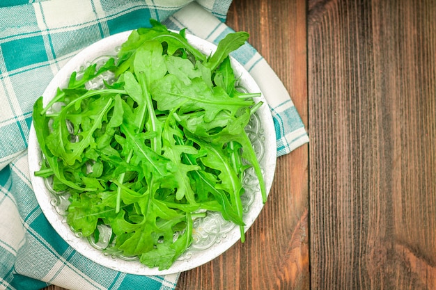 Hojas jugosas frescas del arugula en una tabla de madera marrón.