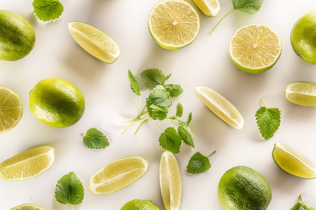 Hojas de limón y menta recién cortadas sobre un fondo blanco.