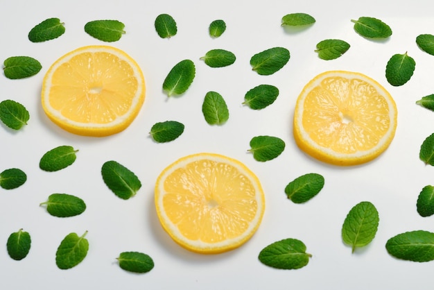 Hojas de menta am rodajas de limón sobre fondo blanco.