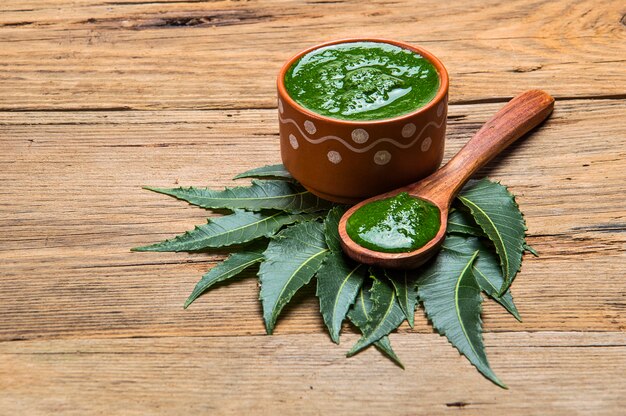 Hojas de neem medicinales con pasta en madera