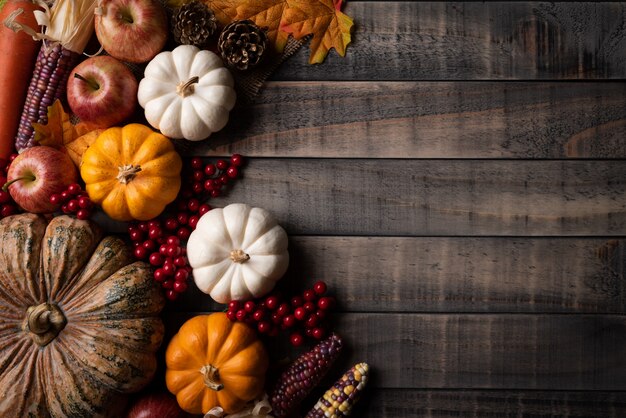 Hojas otoñales de arce con calabaza, maíz y frutos rojos.