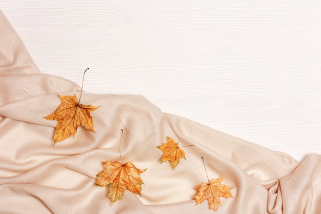 Las hojas de otoño amarillas planas ponen en el fondo de madera blanco con espacio de copia. Hojas naturales de arce y un cálido y acogedor palantino, tema otoñal.