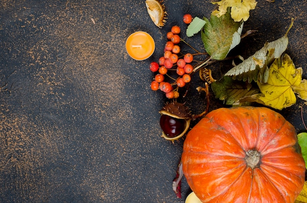 Hojas de otoño, calabaza, castañas, velas en la oscuridad.