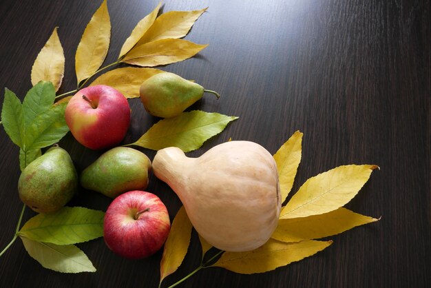 Hojas de otoño y frutas de otoño sobre un fondo de madera negra