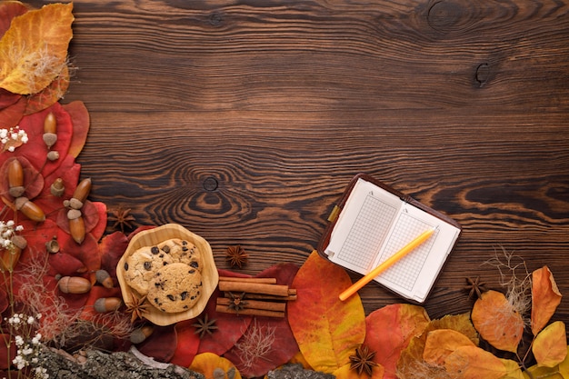 Foto hojas de otoño, galletas y cuaderno de papel sobre madera